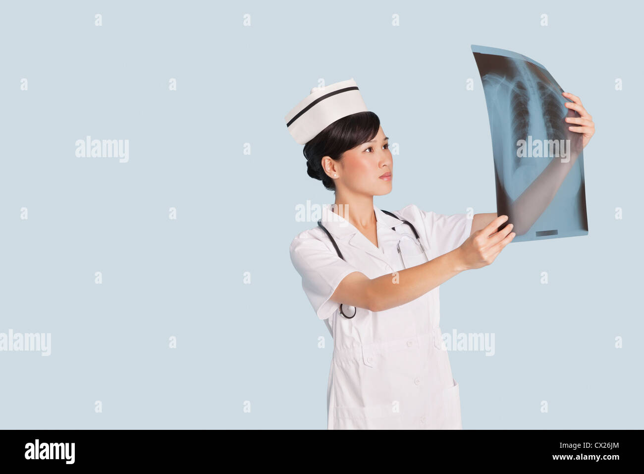 Ärztin, die Analyse der Röntgen-Bericht in hellblauen Hintergrund Stockfoto