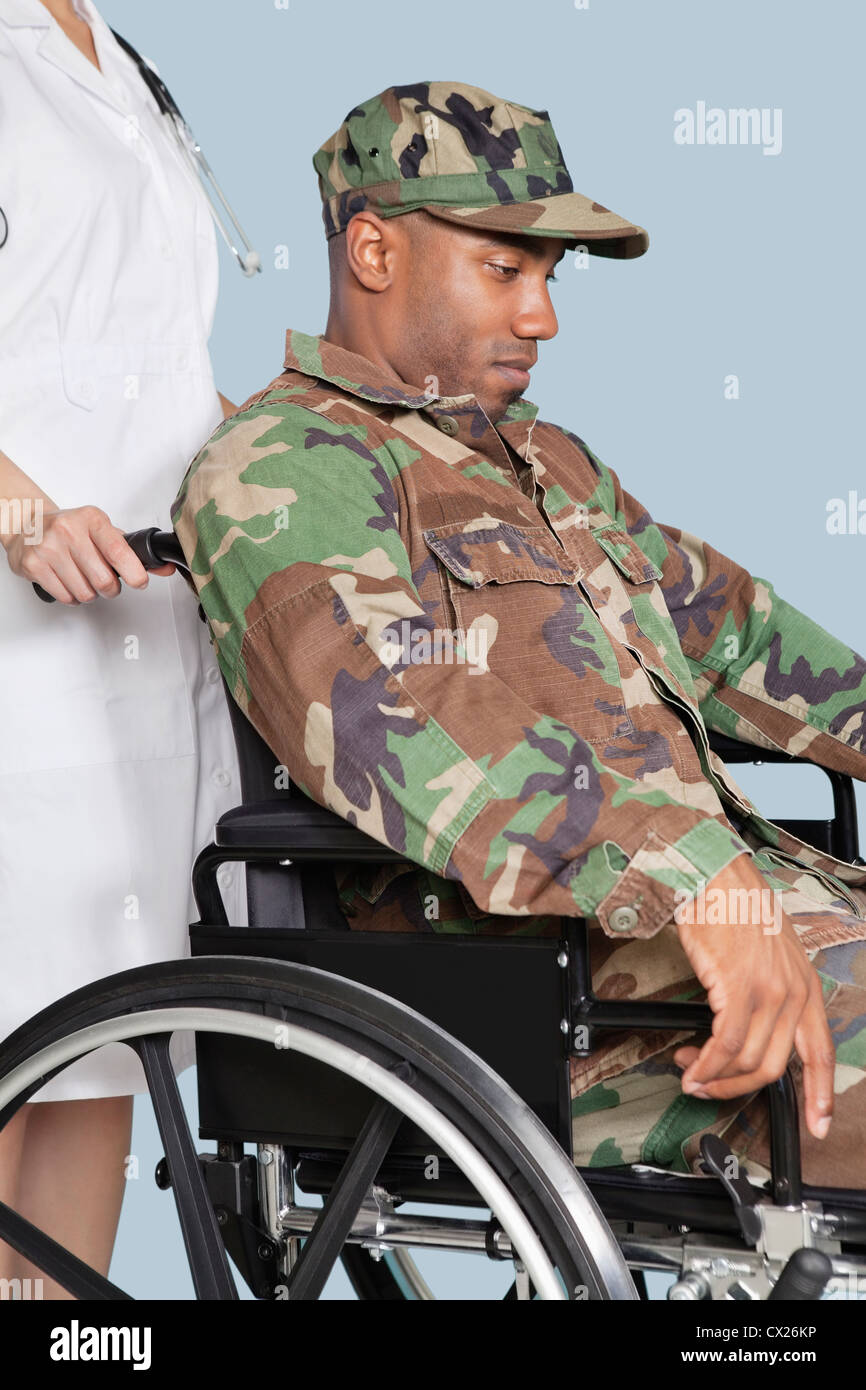Traurige US Marine Corps Soldaten tragen Tarnuniform im Rollstuhl unterstützt von Krankenschwester Stockfoto