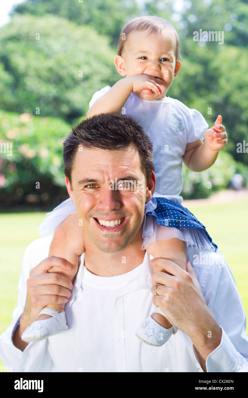 glückliche Tochter auf Vaters Schultern im Freien sitzen Stockfoto