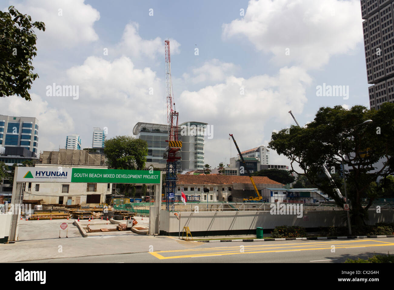 Eine Baustelle in Singapur mit Kränen und eine Menge Arbeit. Die Website ist von hohen Gebäuden und Bäumen umgeben. Stockfoto