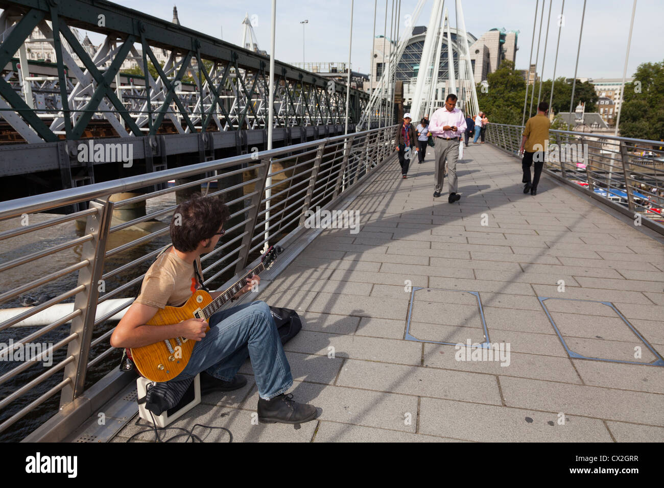 Straßenmusiker spielen e-Gitarre auf der Golden Jubilee Fußgängerbrücke über die Themse von Hungerford Bridge Stockfoto