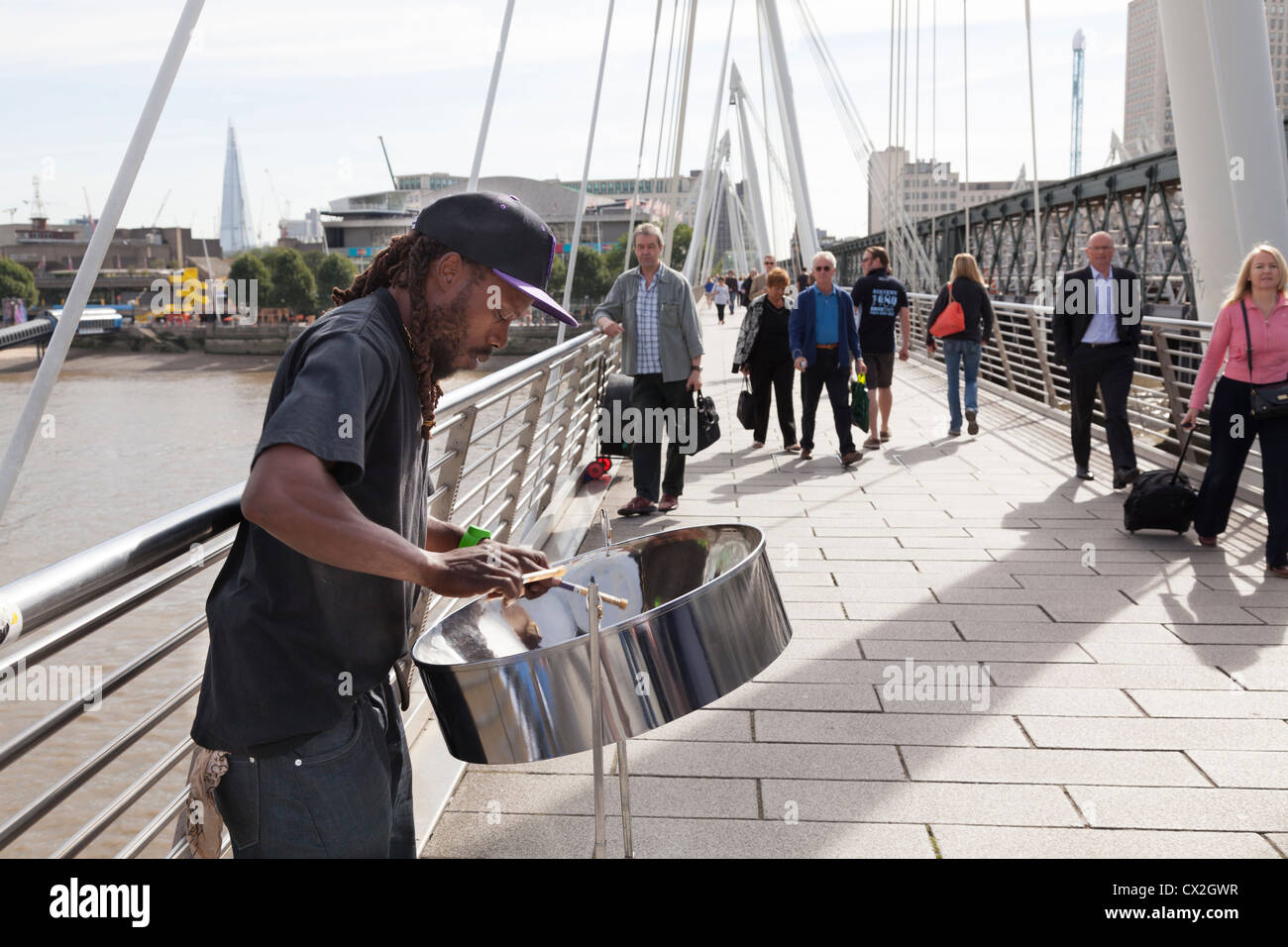 Straßenmusiker spielen Stahlband Trommel (Steelpan) auf der Golden Jubilee Fußgängerbrücke über die Themse von Hungerford Bridge Stockfoto