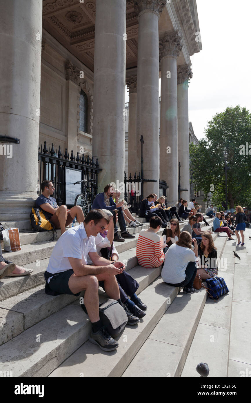 Touristen, die Ruhe auf der Treppe außerhalb St. Martins in den Bereichen Kirche in London Stockfoto