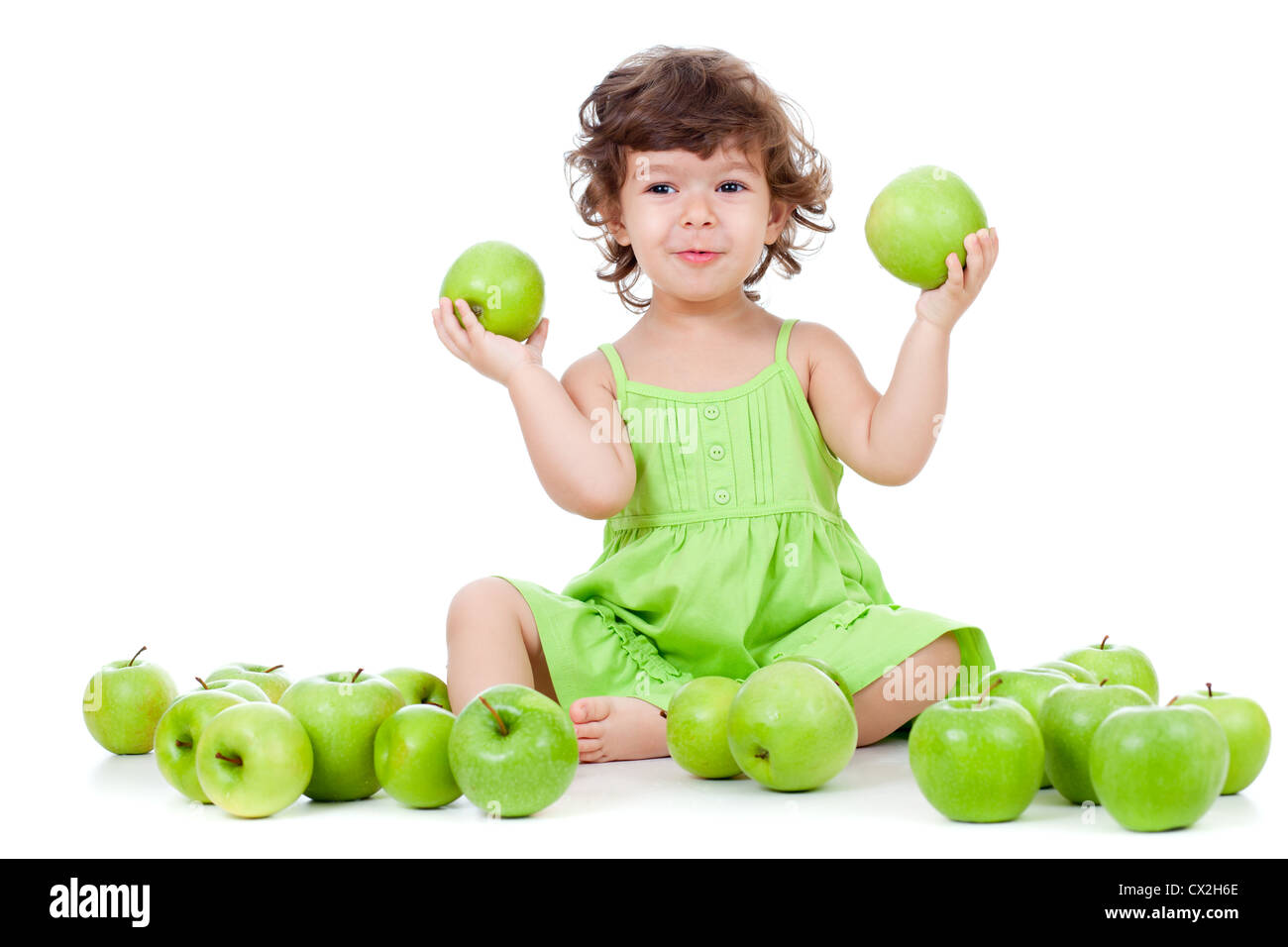 Entzückende kleine Mädchen sitzen mit grünen Äpfeln Stockfoto