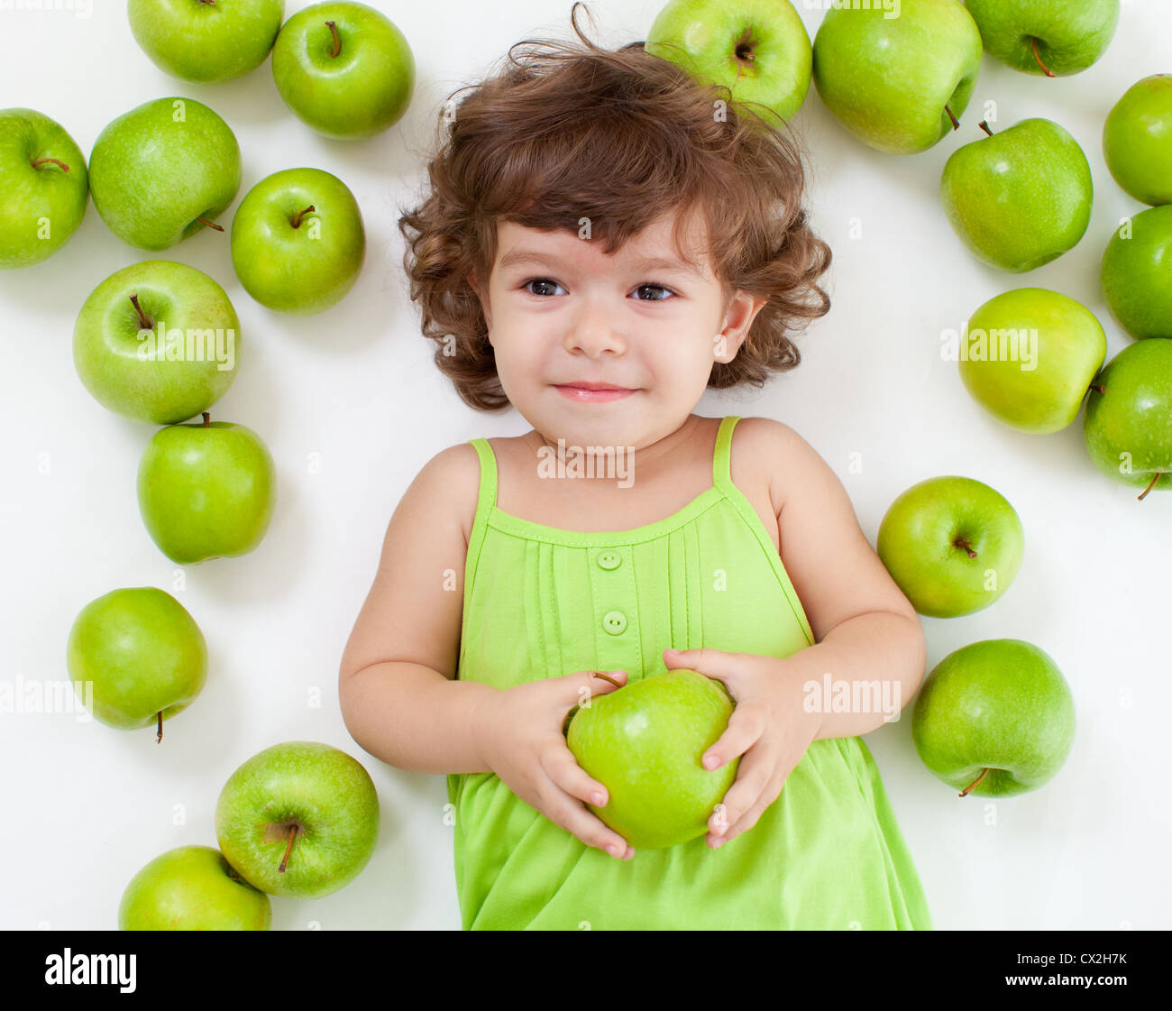 Entzückende kleine Mädchen liegend mit grünen Äpfeln Stockfoto