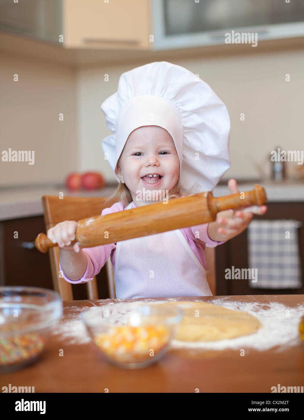 Kleines Mädchen macht den Teig auf Küche mit Nudelholz Stockfoto