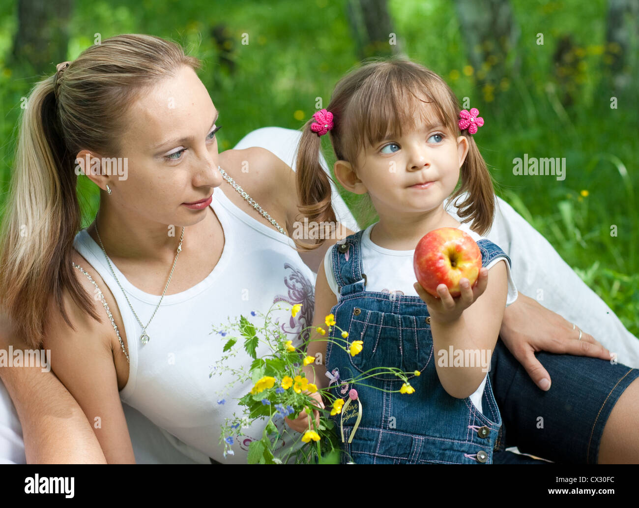 Liegen Mutter und Tochter in Jeans mit Apple im freien Stockfoto