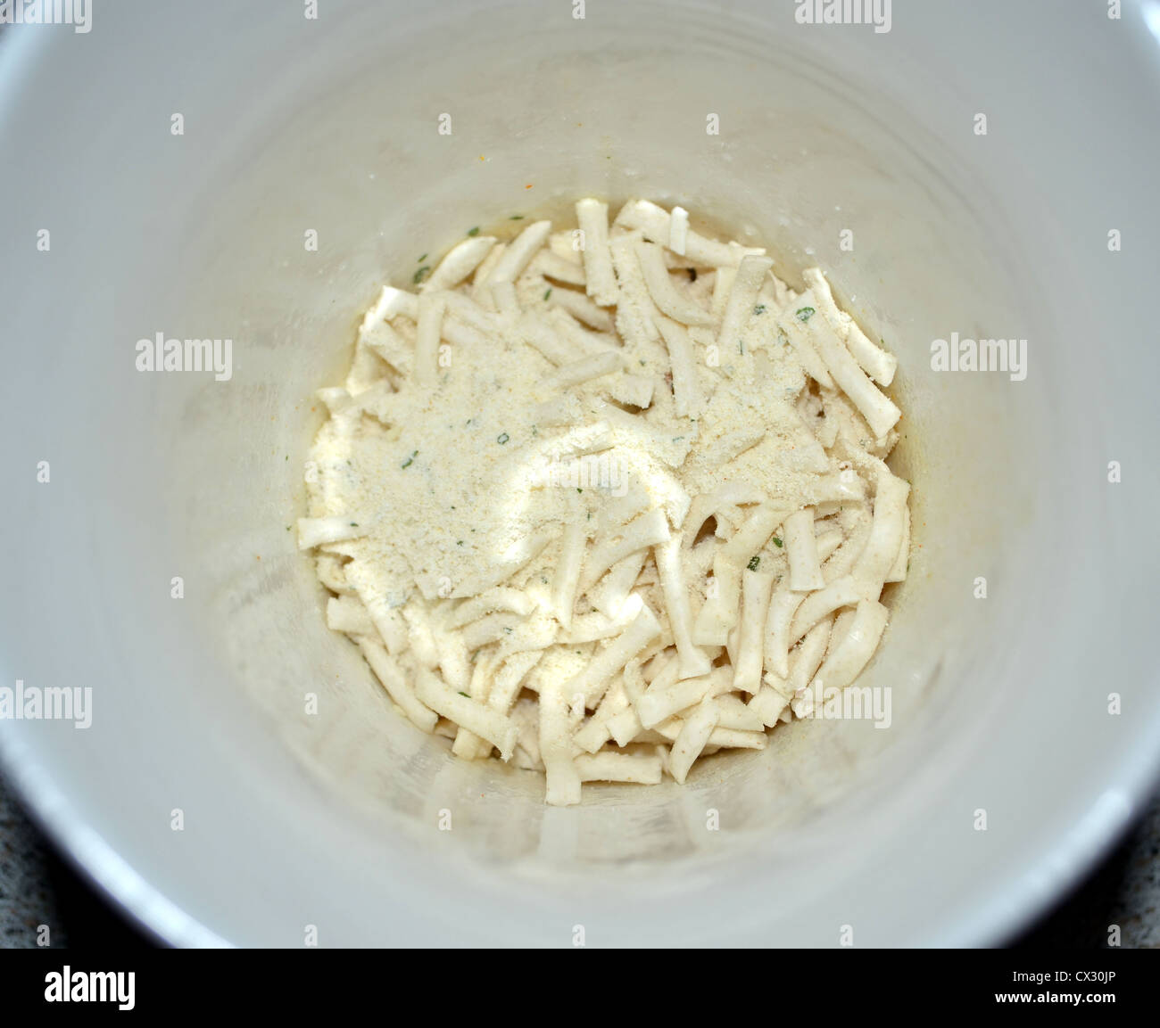 Birdseye Blick auf getrocknete Nudeln und Aromastoff in eine Tasse kochendes Wasser gießen warten unten Stockfoto