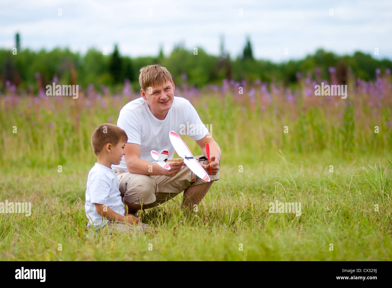 Vater und Sohn starten Flugzeugmodell in Sommerwiese Stockfoto