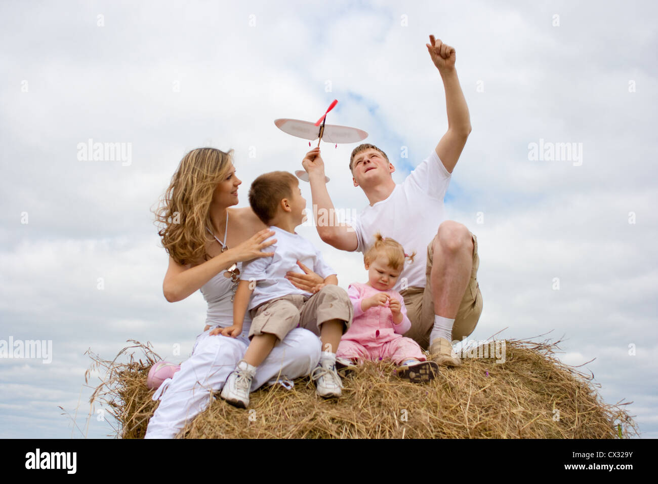 Glückliche Familie startende Flugzeuge Spielzeugmodell Zusammensitzen auf Heuhaufen Stockfoto