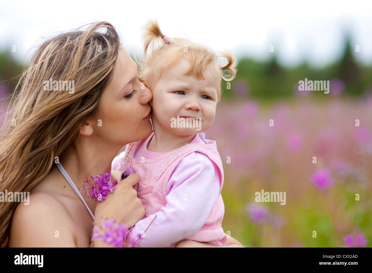 Mutter küssen Tochter auf Wiese im freien Stockfoto