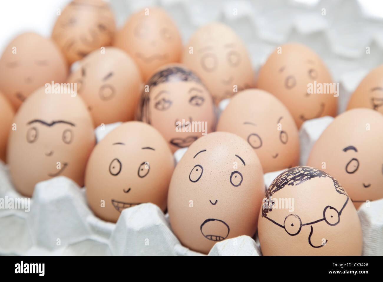 Verschiedene Gesichtsausdrücke gemalt braune Eier im Eierkarton Stockfoto