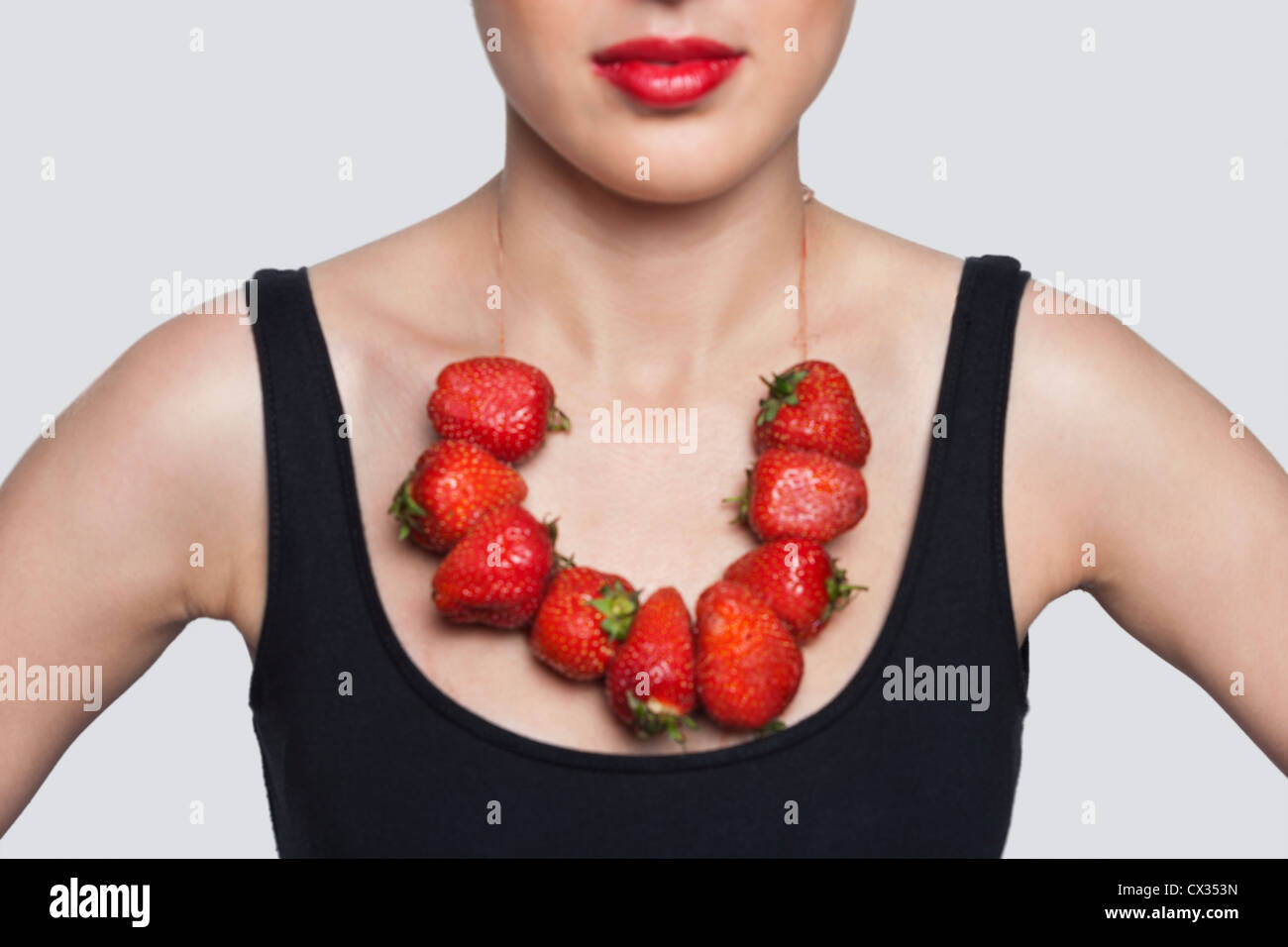 Innenfeldes von einer Frau mit Erdbeer Halskette über grauen Hintergrund Stockfoto