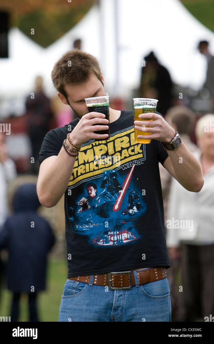 Mann mit zwei Getränke in Plastikbechern, Eurofair Essen und trinken Festival, Canterbury, Kent, England, UK Stockfoto