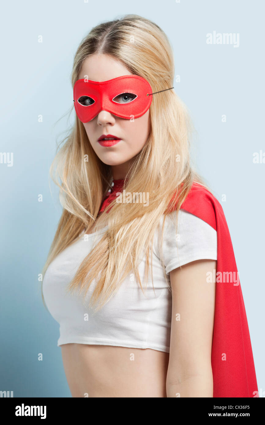 Porträt der jungen Frau mit Superhelden-Kostüm vor blauem Hintergrund Stockfoto