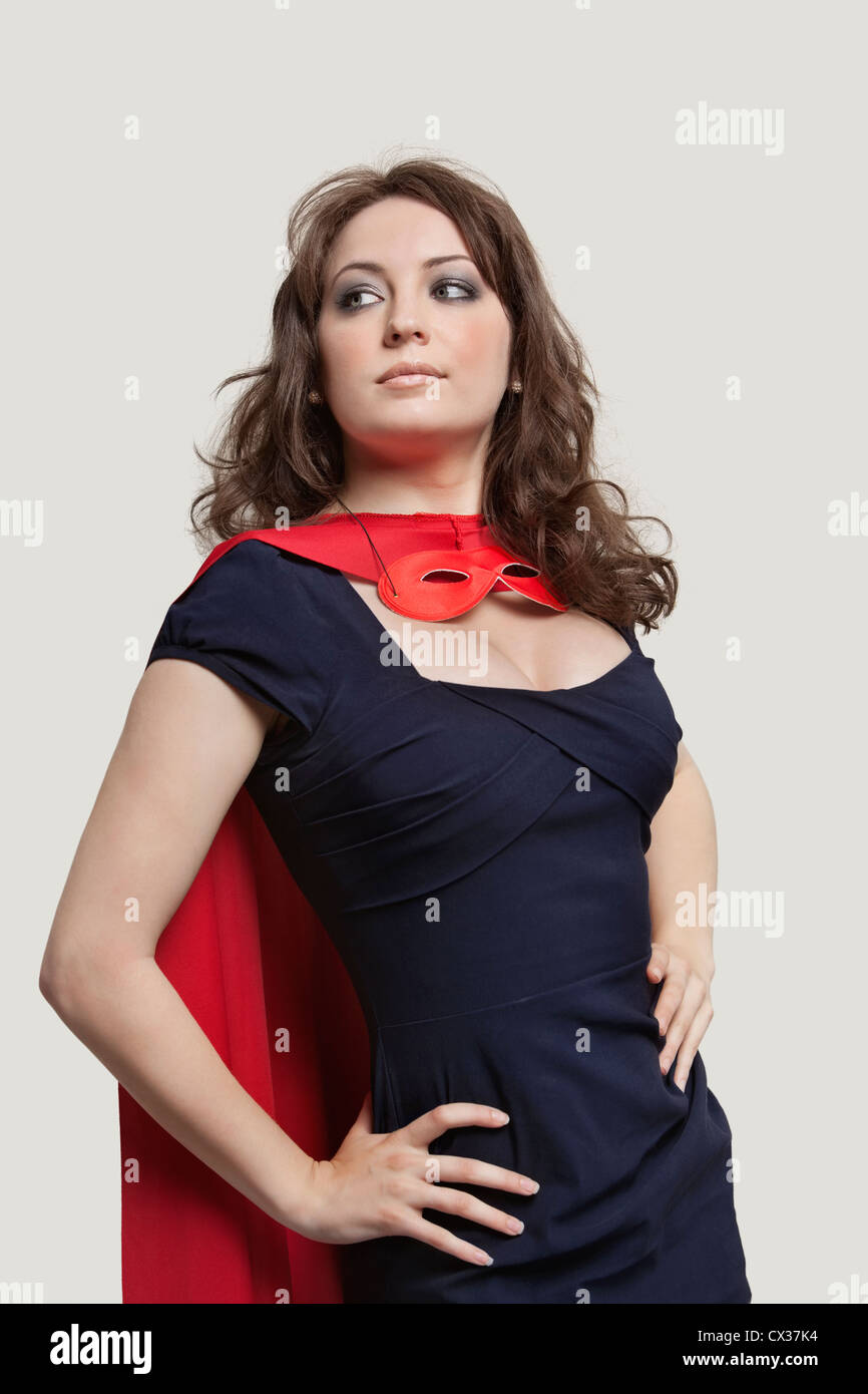 Schöne Frau in Superhelden-Kostüm auf grauem Hintergrund Stockfoto
