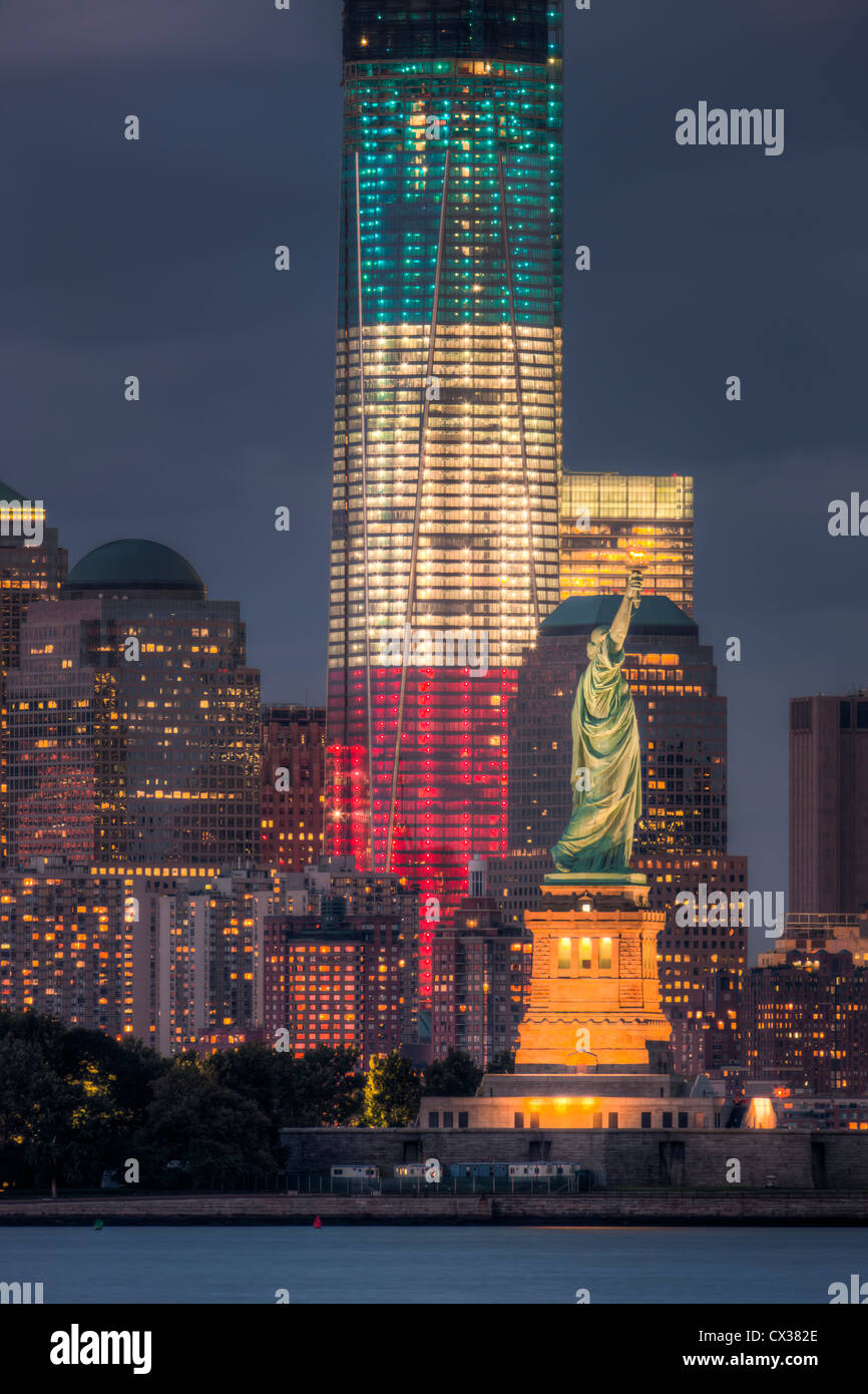 Zwei Symbole der Freiheit, der Freiheitsstatue und der Freedom Tower in rot, weiß und blau leuchtet, leuchtet in der Dämmerung in New York City. Stockfoto