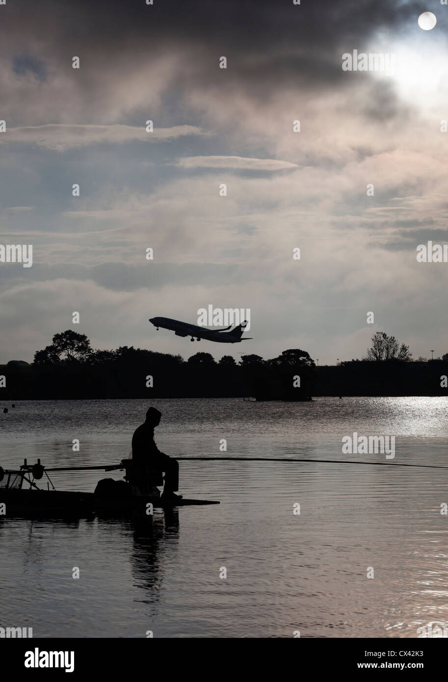 Mann Angeln in Yeadon Tarn, wie ein Flugzeug vom Flughafen Leeds Bradford startet. Stockfoto