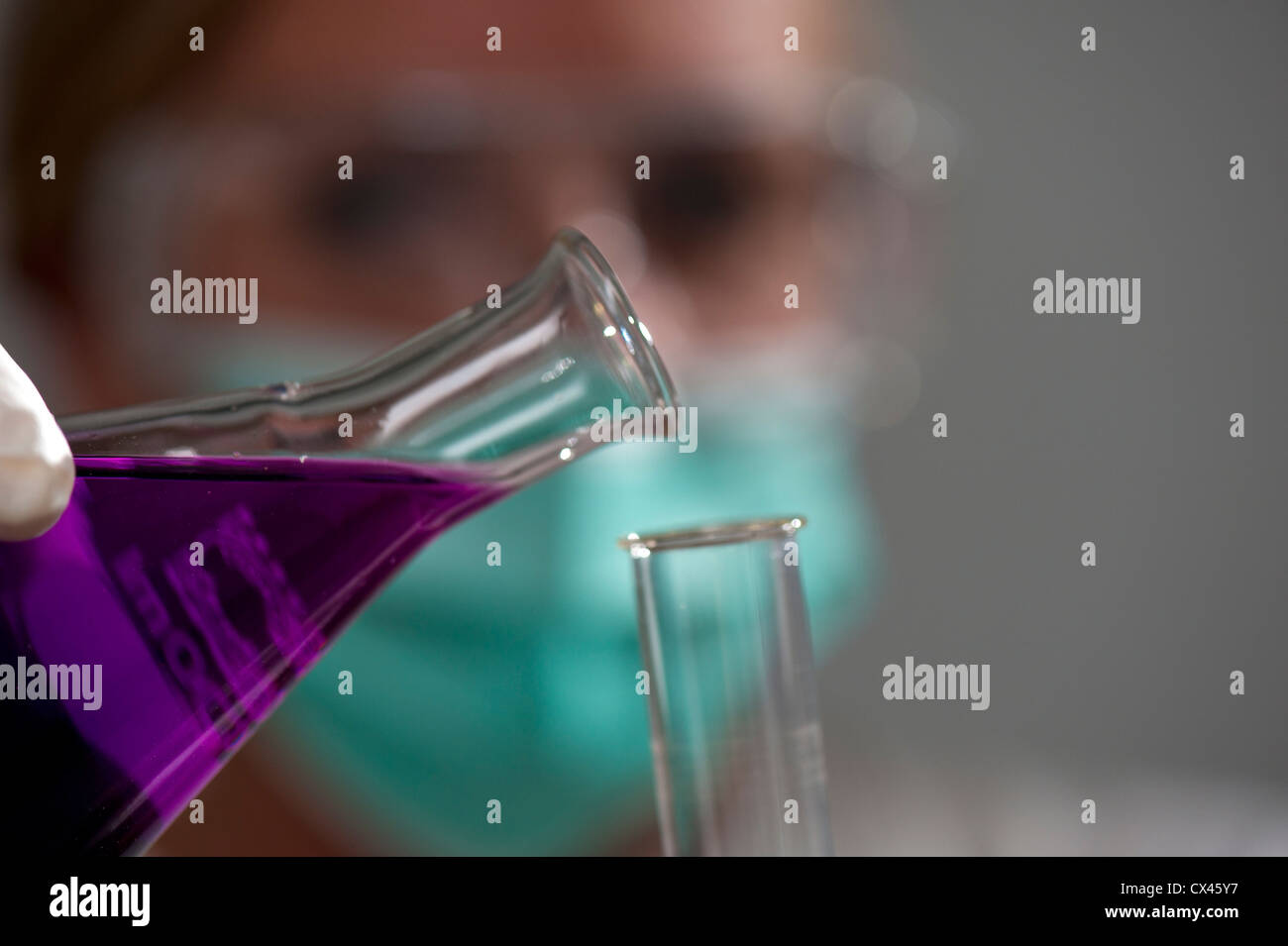 Chemiker kippt Flüssigkeit aus einer Flasche in ein Reagenzglas Stockfoto