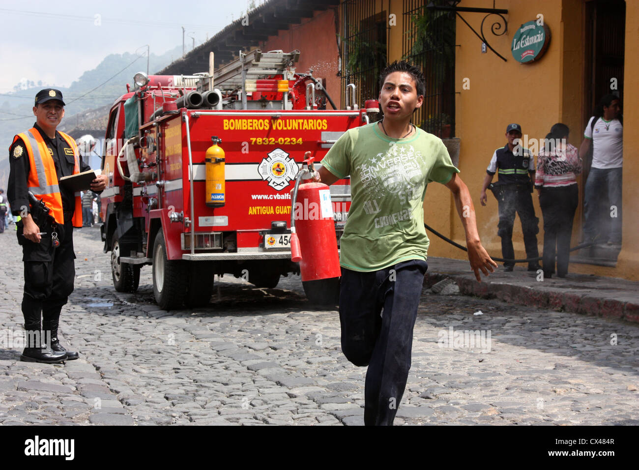 Kellner Mann eilt zum Feuerlöscher als Besatzungen Kampf um Restaurant in Flammen in Antigua, Guatemala-Mittelamerika Feuer Nachfüllen Stockfoto