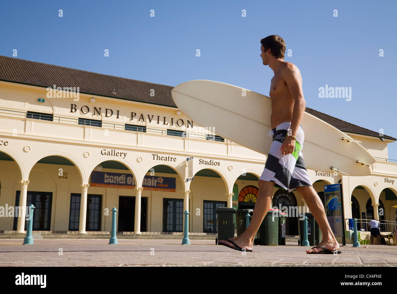 Mann tragenden Surfbrett zu Fuß entlang der Promenade. Bondi Beach, Sydney, New South Wales, Australien Stockfoto