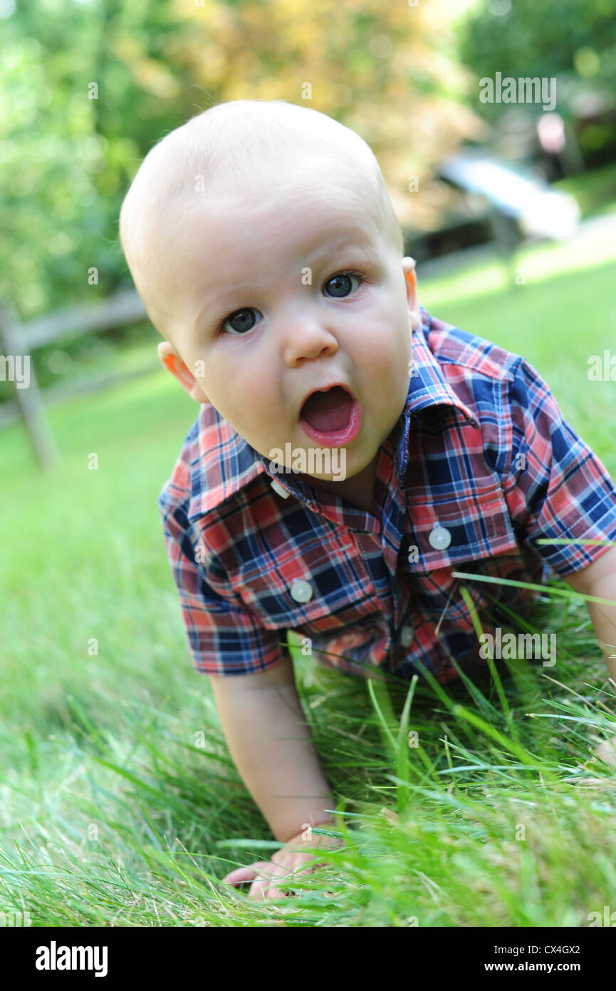 Weiße kaukasische Baby krabbeln Gras im Sommer 7 Monate alt aussehen der Überraschung Freude Freude Wunder Stockfoto