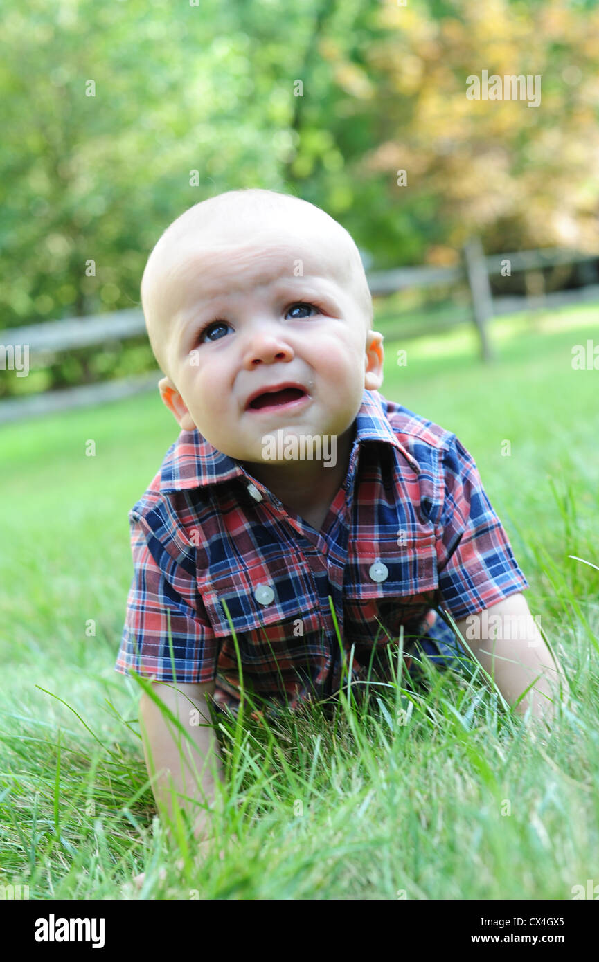 Weißen kaukasischen Baby krabbeln Gras im Sommer 7 Monate alt alt besorgt blickte besorgt Stockfoto