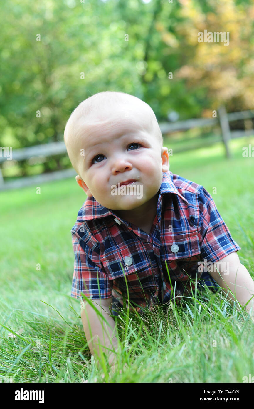 Weiße kaukasische Baby krabbeln Gras im Sommer 7 Monate alt ernsten Blick Stockfoto
