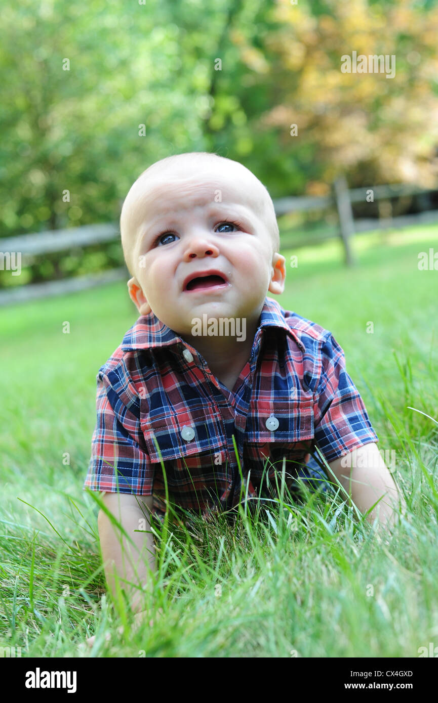 Weißen kaukasischen Baby krabbeln Gras im Sommer 7 Monate alt blickte besorgt besorgt Stockfoto