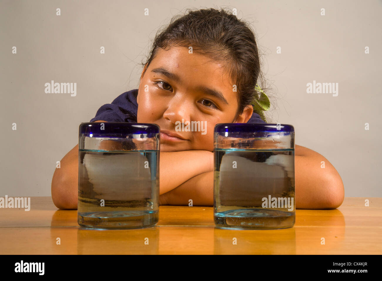 Ein Kind sieht bei identischen Gläser gefüllt mit der gleichen Menge Flüssigkeit Piagets flüssige Erhaltung Experiment nachweisen. Stockfoto