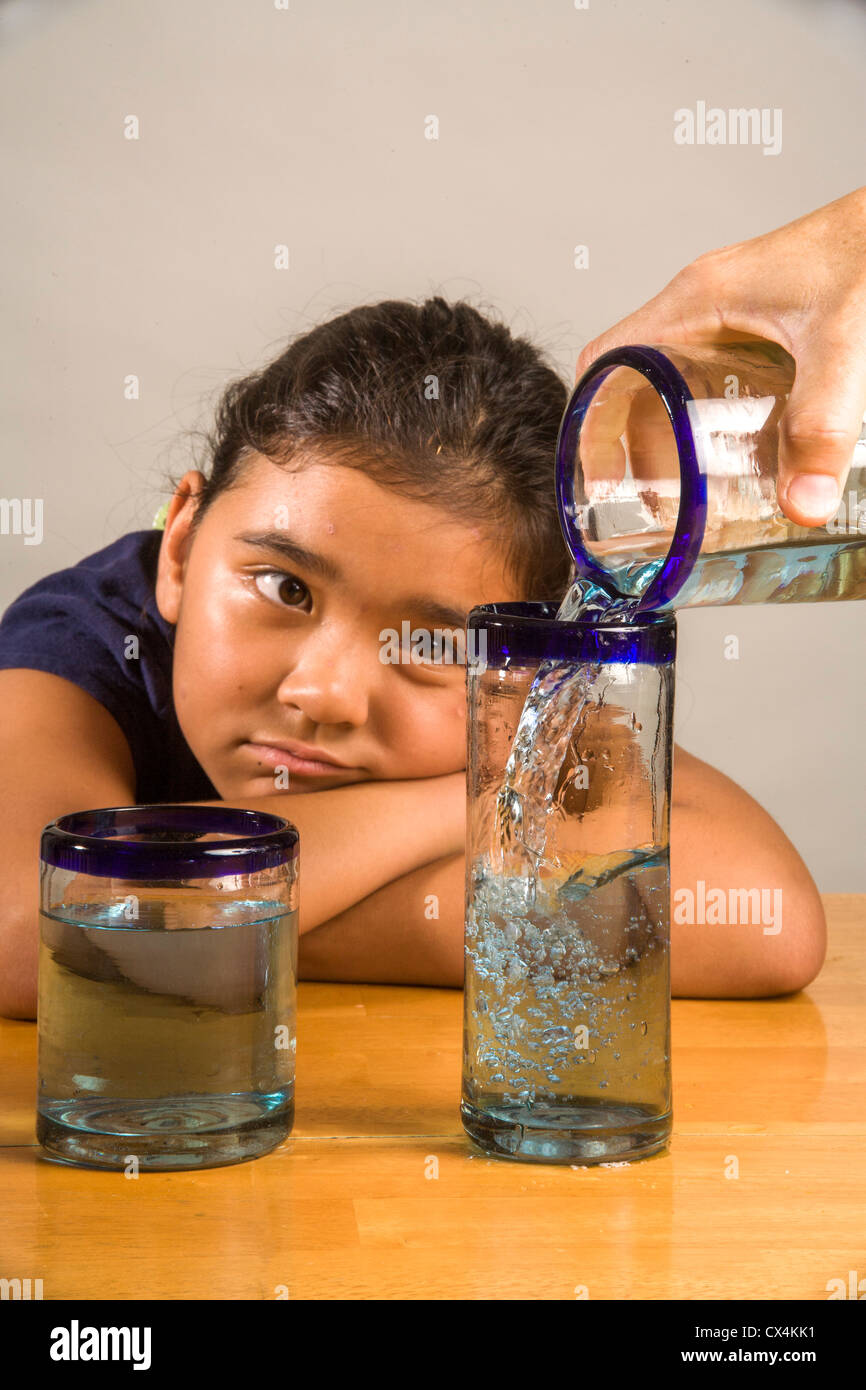 Ein Kind sieht bei identischen Gläser gefüllt mit der gleichen Menge Flüssigkeit Piagets flüssige Erhaltung Experiment nachweisen. Stockfoto