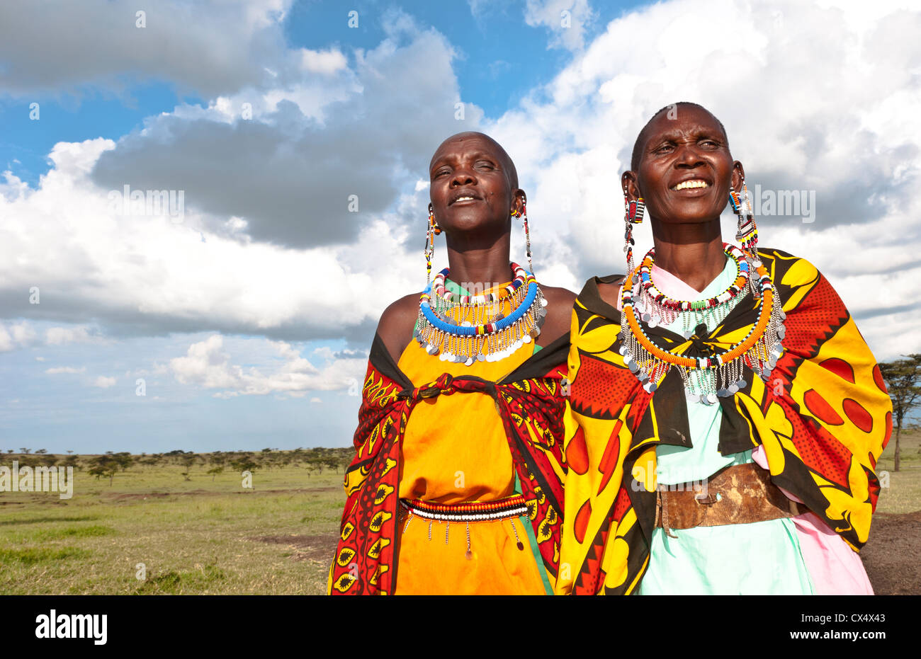 Kenia-Masai-Mara-Reservat mit zwei Massai-Frauen in bunten Kleid mit blauem Himmel in Masai Mara National Park Reserve #10 Stockfoto