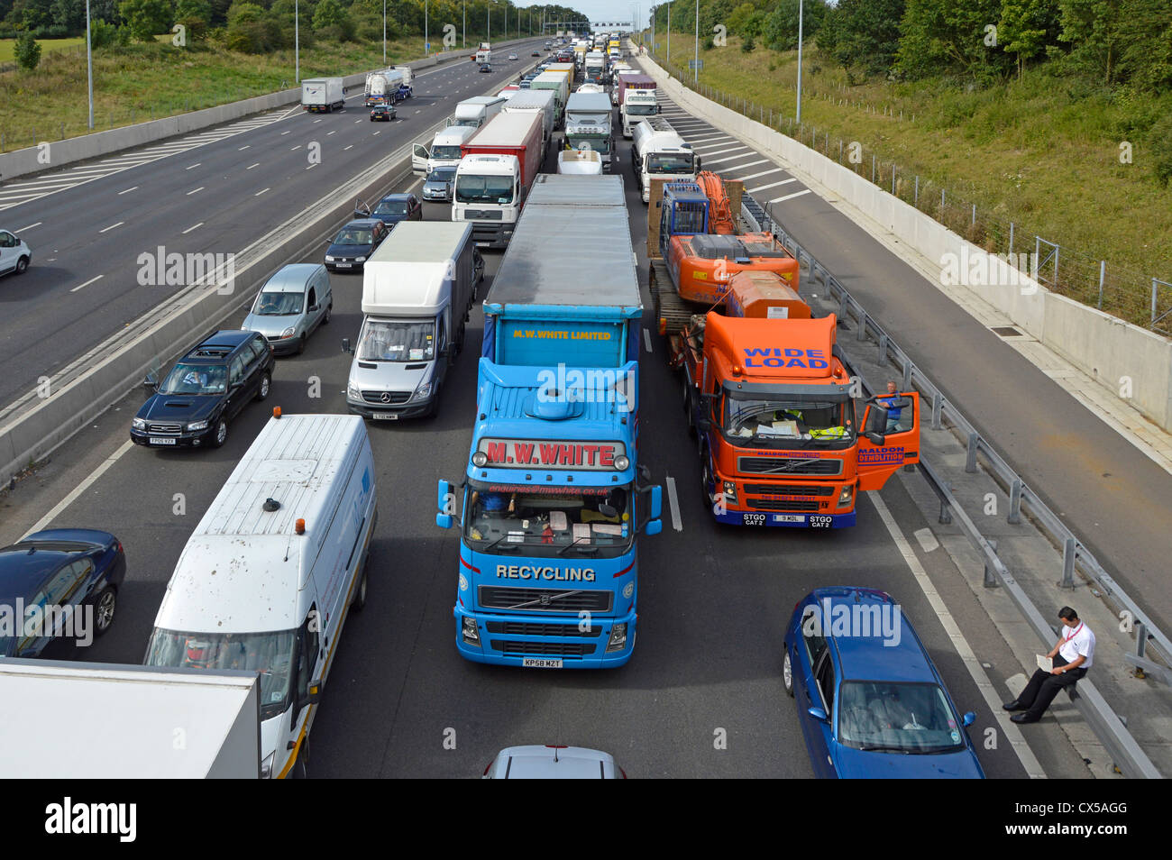 Autofahrer sitzt auf der Unfallbarriere mit Verkehrsschwelle und ist auf vier Spuren der Autobahn Essex England UK M25 gesperrt Stockfoto