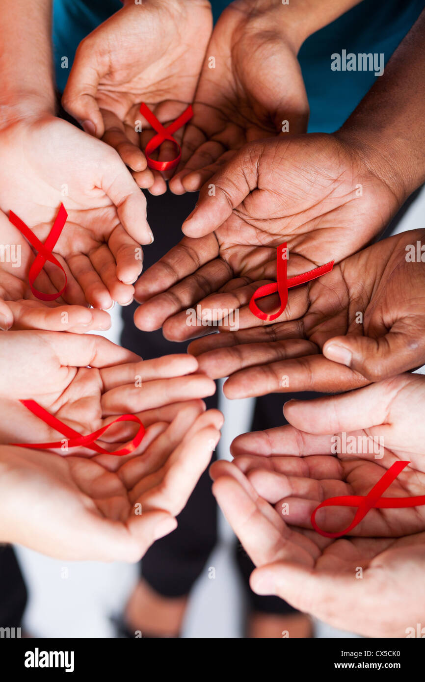 Gruppe von Rassen Menschen halten rote Schleife für HIV AIDS awareness Stockfoto