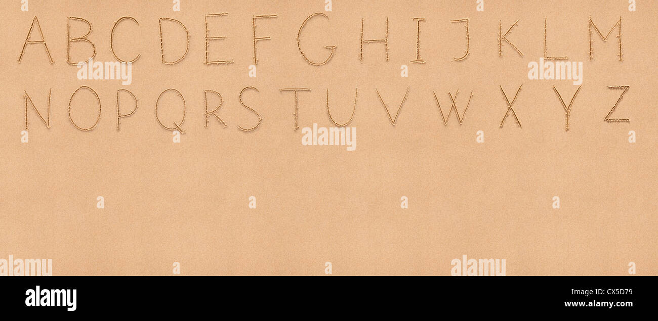 Englisches Alphabet Handschrift auf flachen Sand mit dem leeren Raum als Hintergrund für Ihren Text geeignet Stockfoto