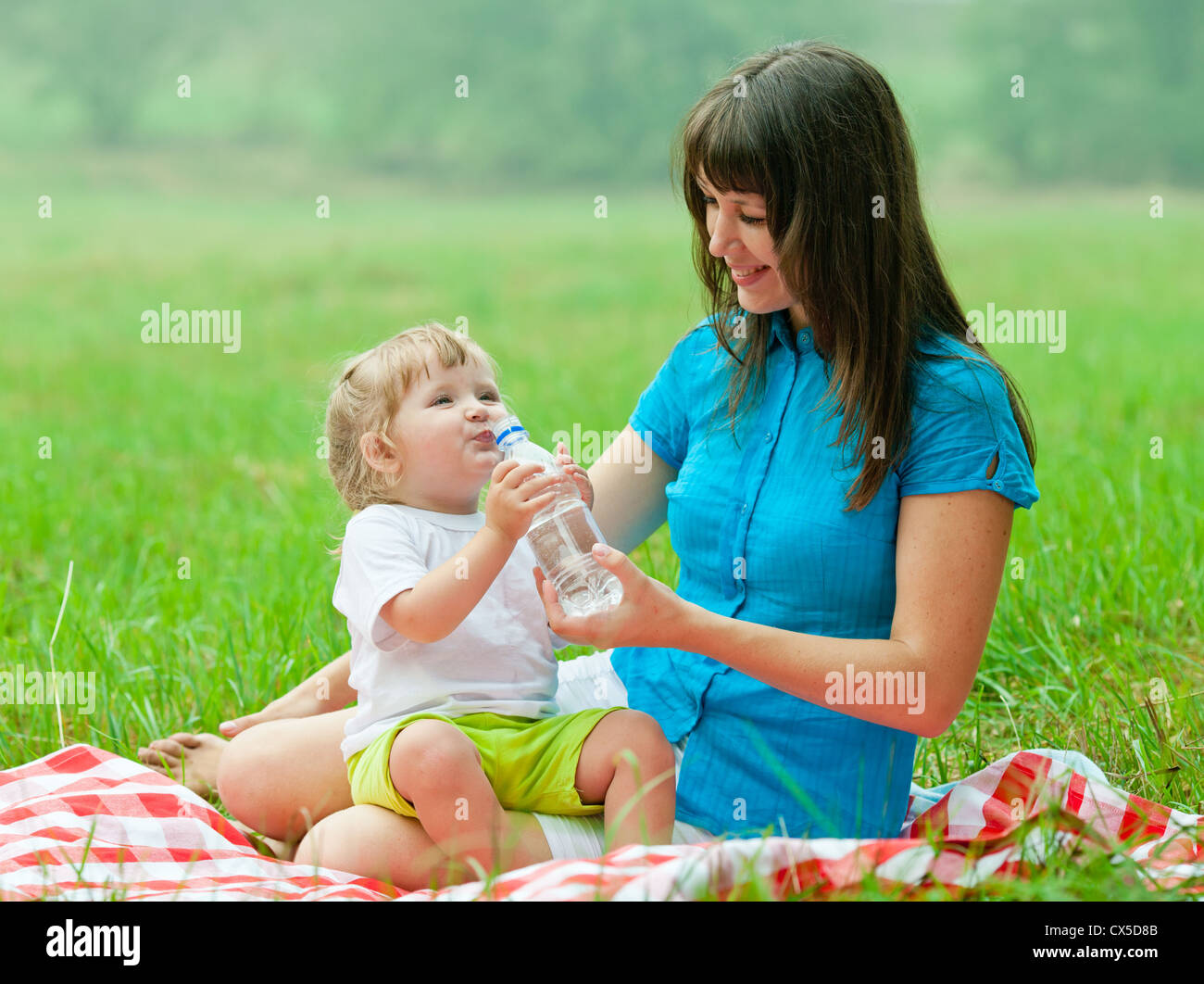 glückliche Mutter und Tochter trinken klares Wasser aus Flasche Stockfoto