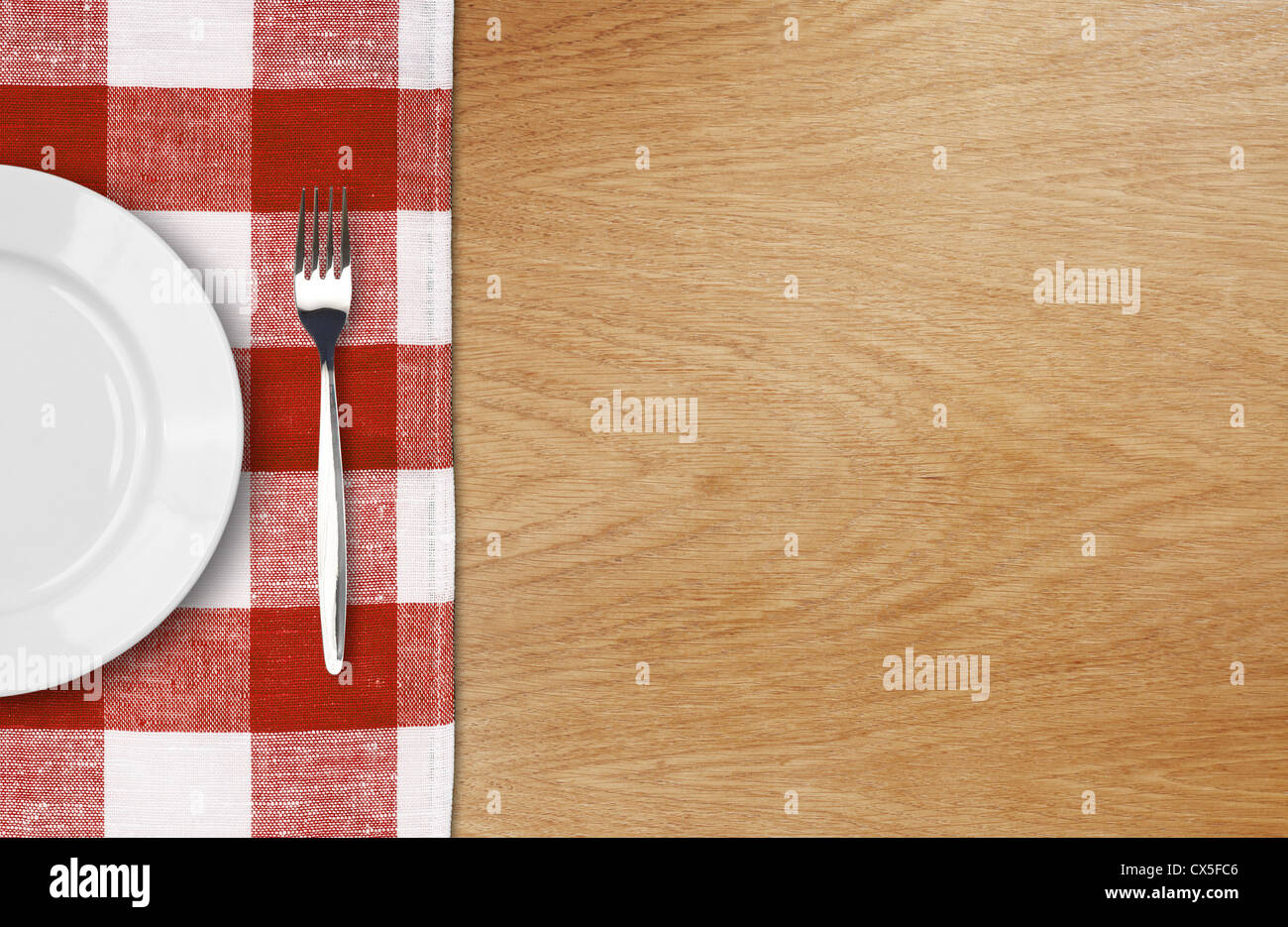 weißen Teller und Gabel auf Holztisch mit roten aufgegebenes Tischdecke und Exemplar Stockfoto