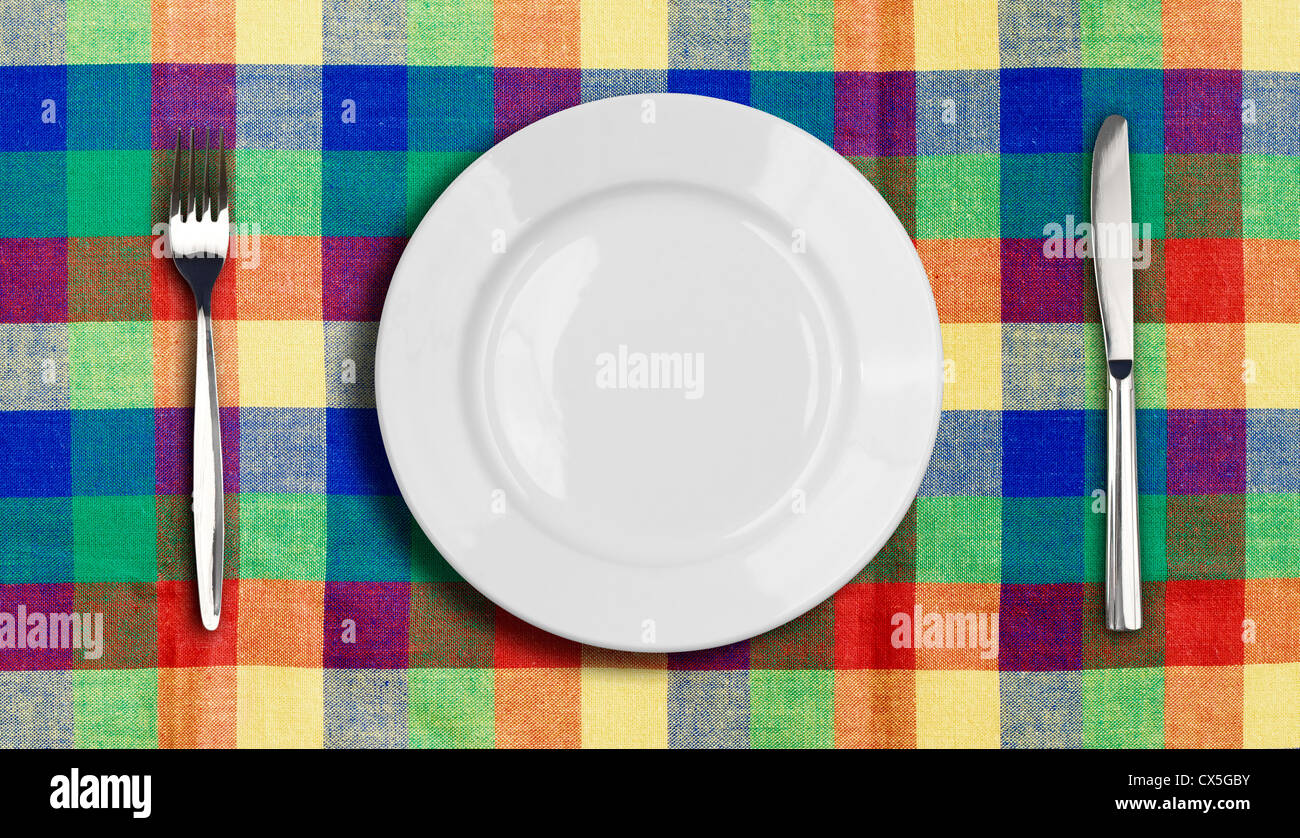 Messer, Teller und Gabel auf multicolor aufgegebenes Tischdecke Stockfoto