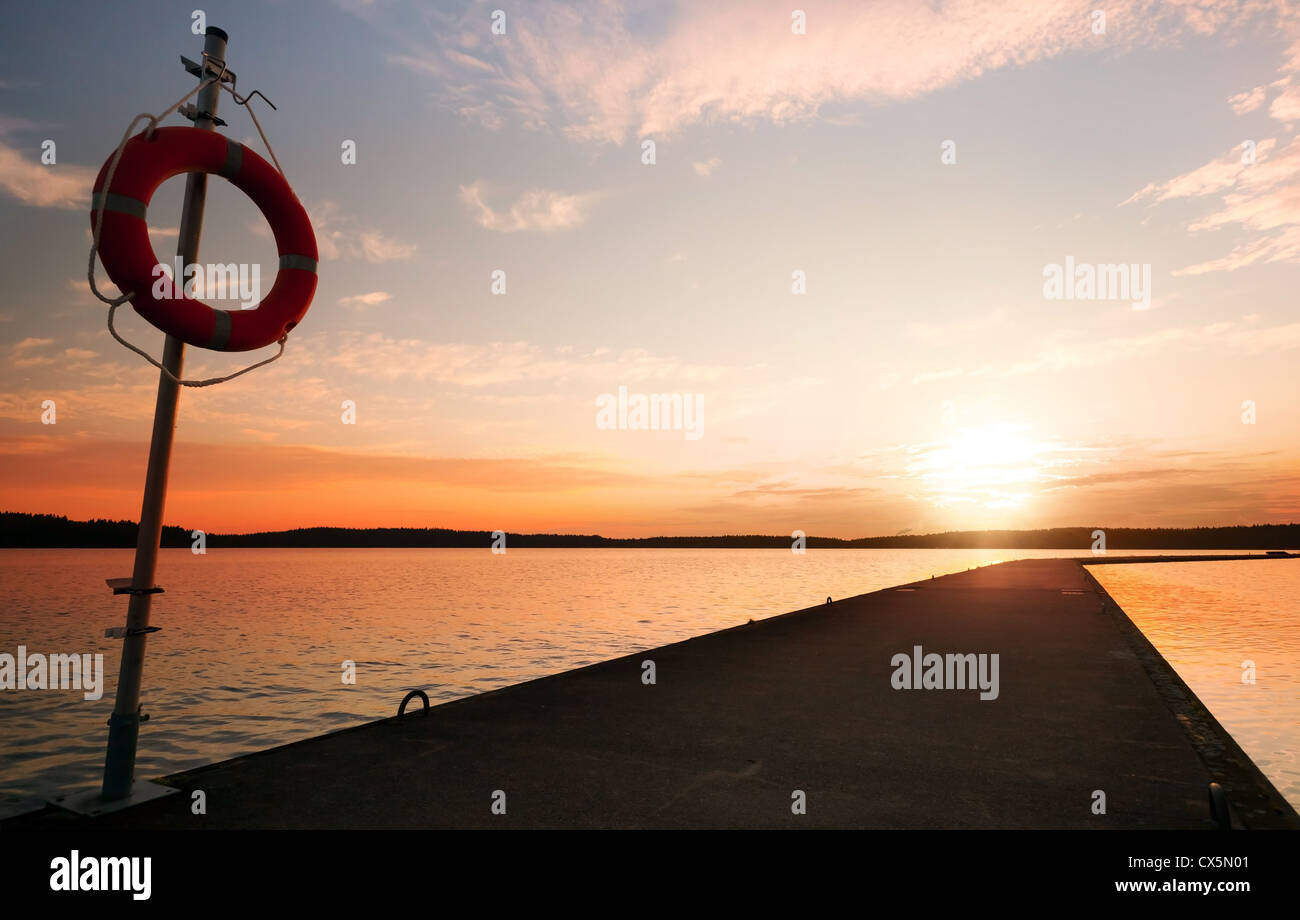 Sicherheitsausrüstung. Rettungsring auf dem Pier im orange sunrise Stockfoto