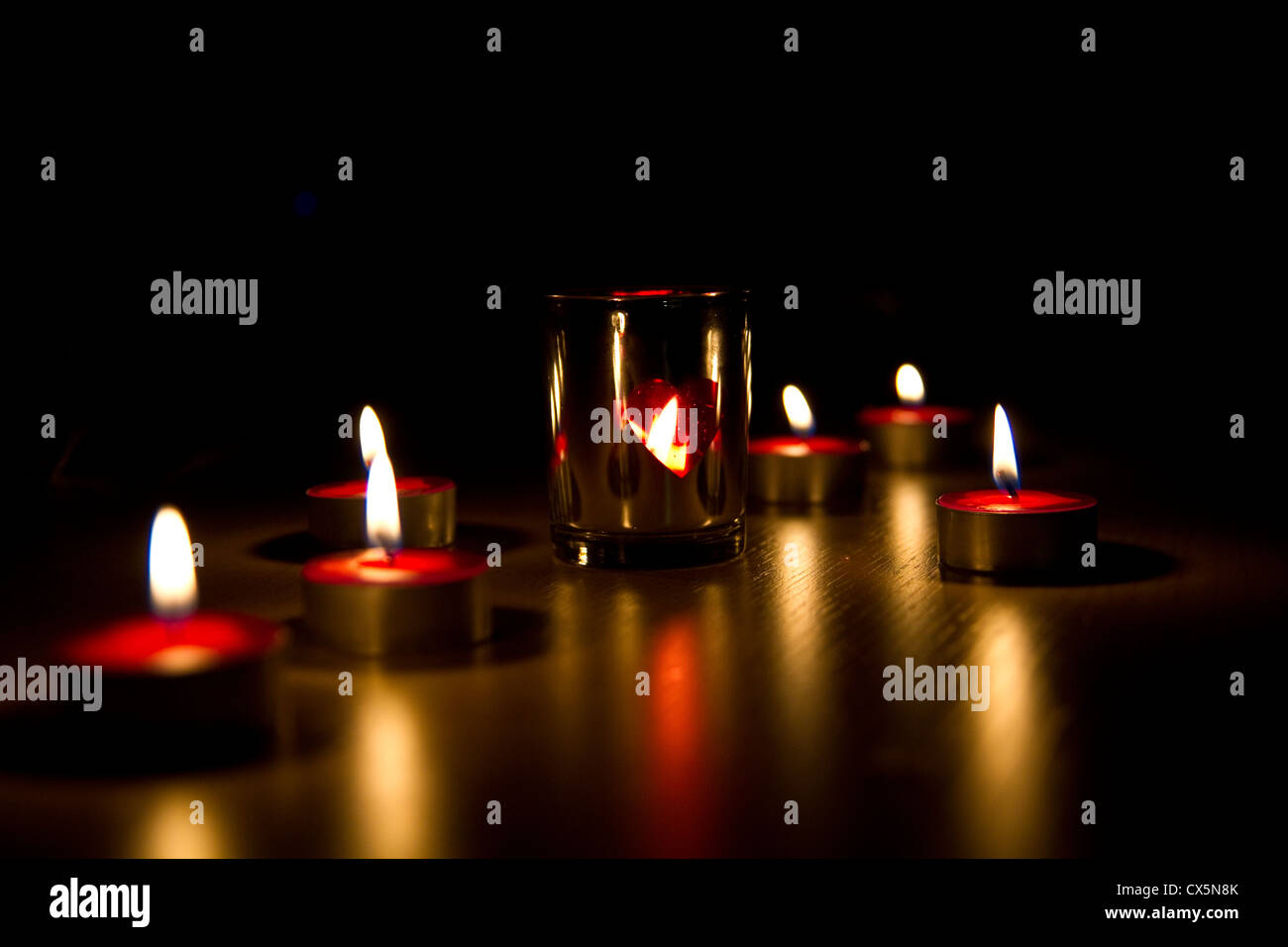 Kleine rote Teelicht Kerzen rund um eine metallische Kerzenhalter, in der Nacht Stockfoto