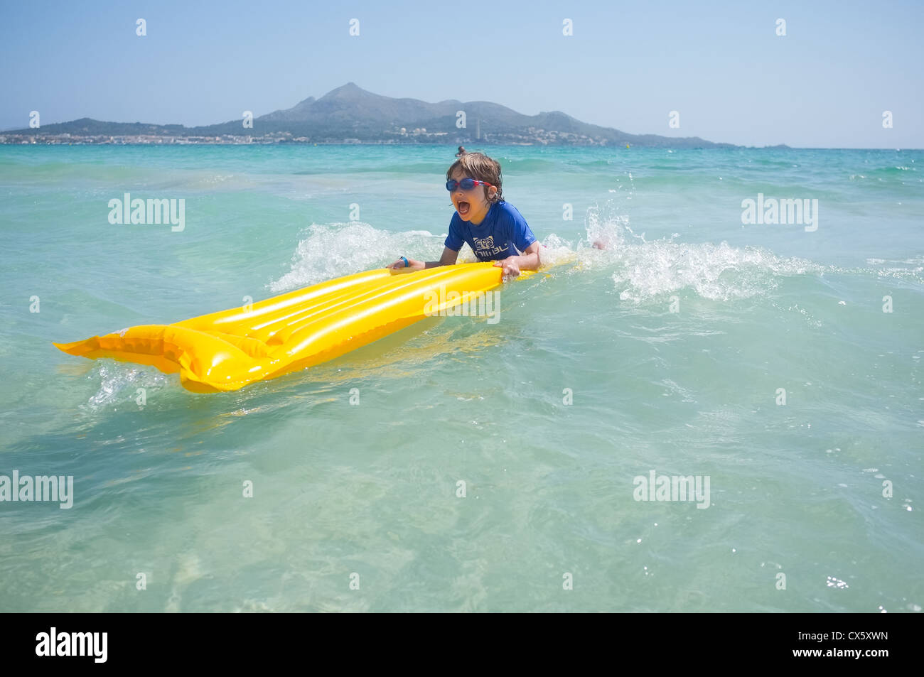 ein kleiner Junge mit Spaß spielen in der Brandung auf einem Schlauchboot Lilo Stockfoto