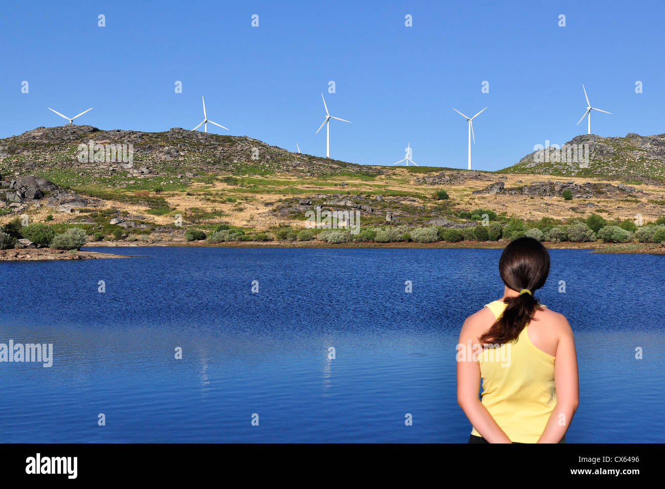 Frau eine Windmühle über einen See betrachten. Konzentriert sich auf die Windräder und die Frau ist leicht unscharf. Stockfoto