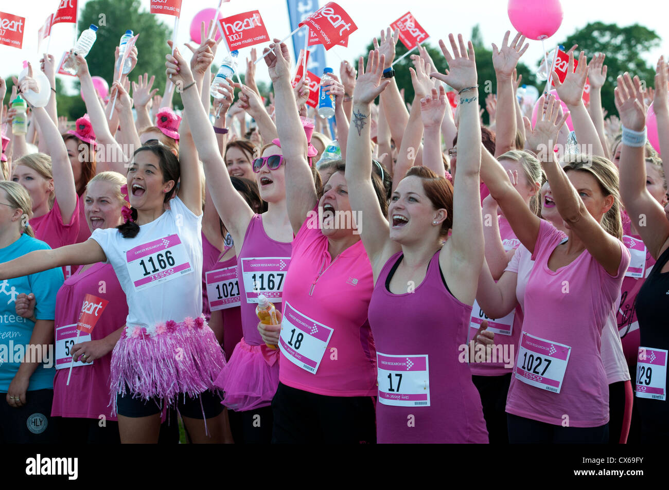 Frauen mit Armen vor dem Rennen für das Leben in Stratford Racecourse. Stockfoto