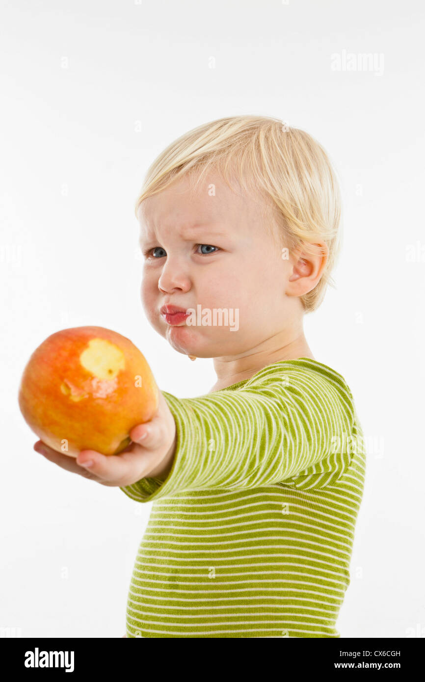 Ein Kleinkind Grimasse einen Apfel mit gedrückter Stockfoto