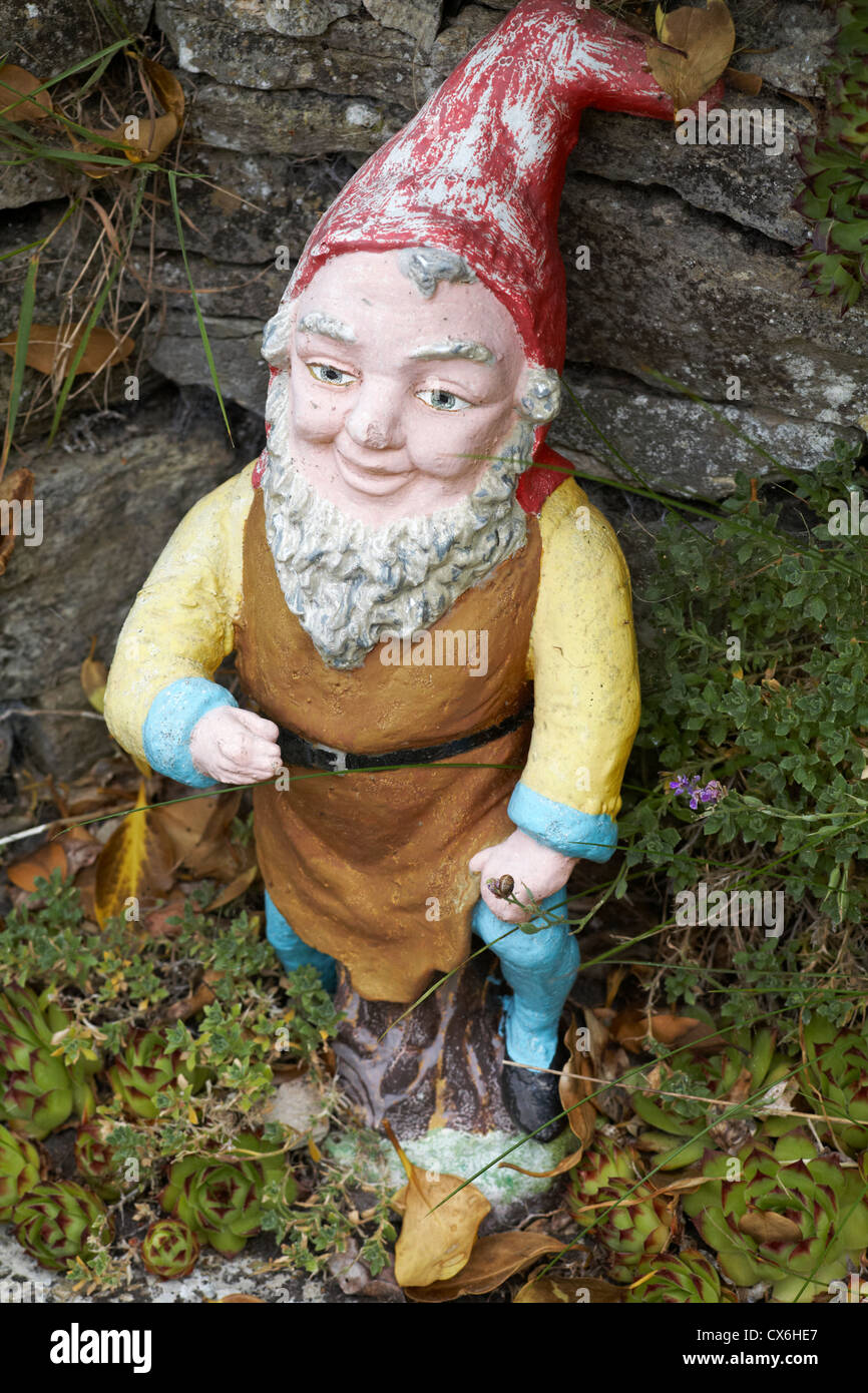 Verwitterte Gartenzwerg mit Hand am Knie Stockfoto