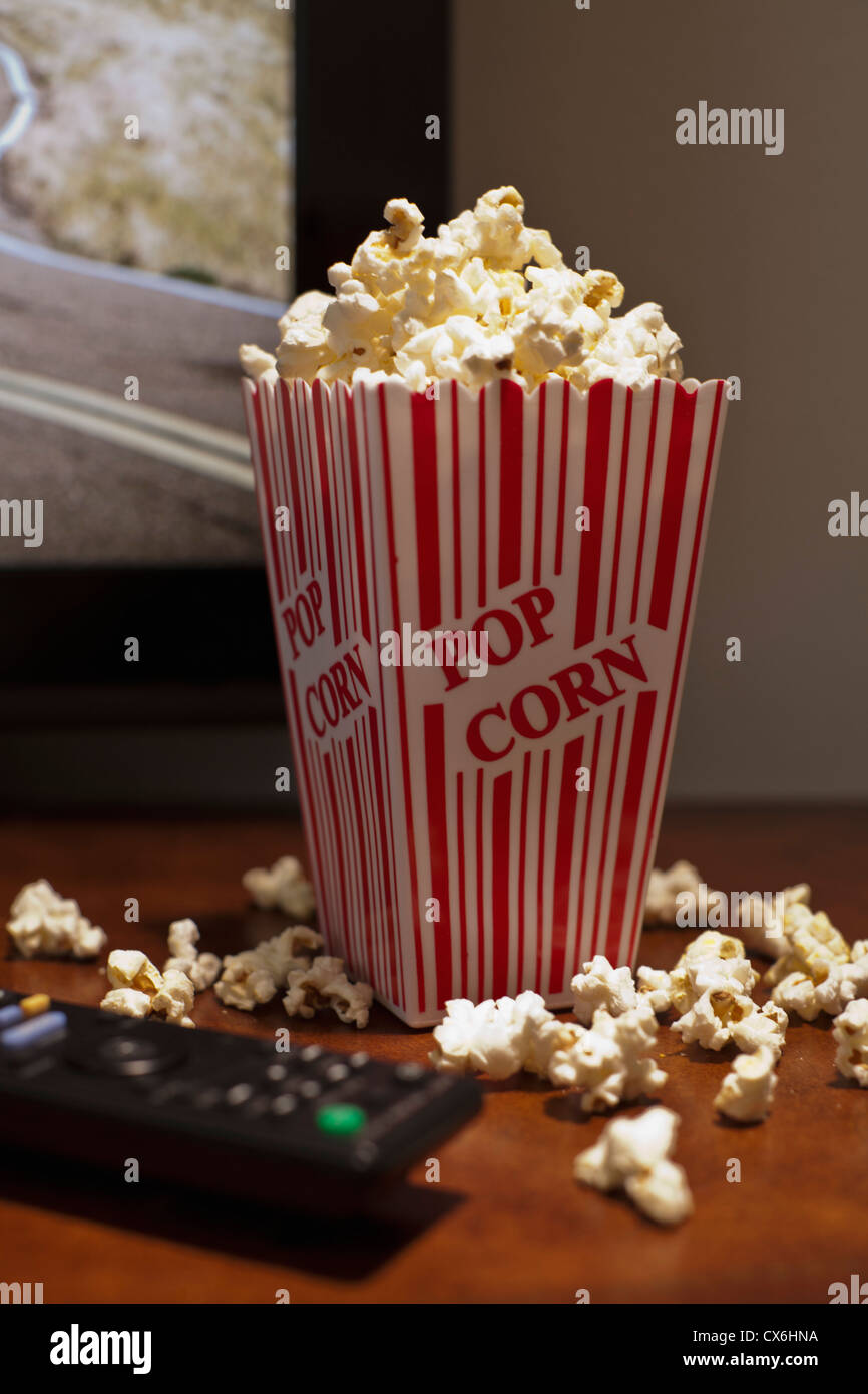Ein rot gestreiften Karton Popcorn auf einem Tisch vor einem Flachbild-TV Stockfoto