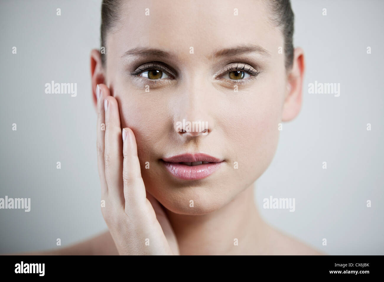 Eine junge Frau, die Berührung der Haut im Gesicht, beschnitten Stockfoto