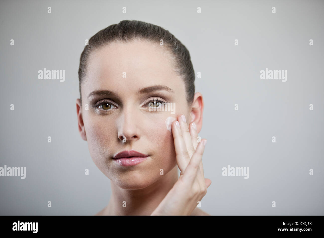 Eine junge Brünette Frau ihr Gesicht Feuchtigkeitscreme zuweisen Stockfoto