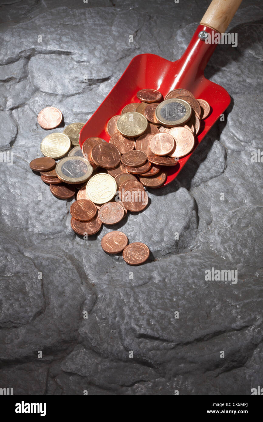Eine rote Schaufel mit einem Haufen von Euro-Münzen Stockfoto