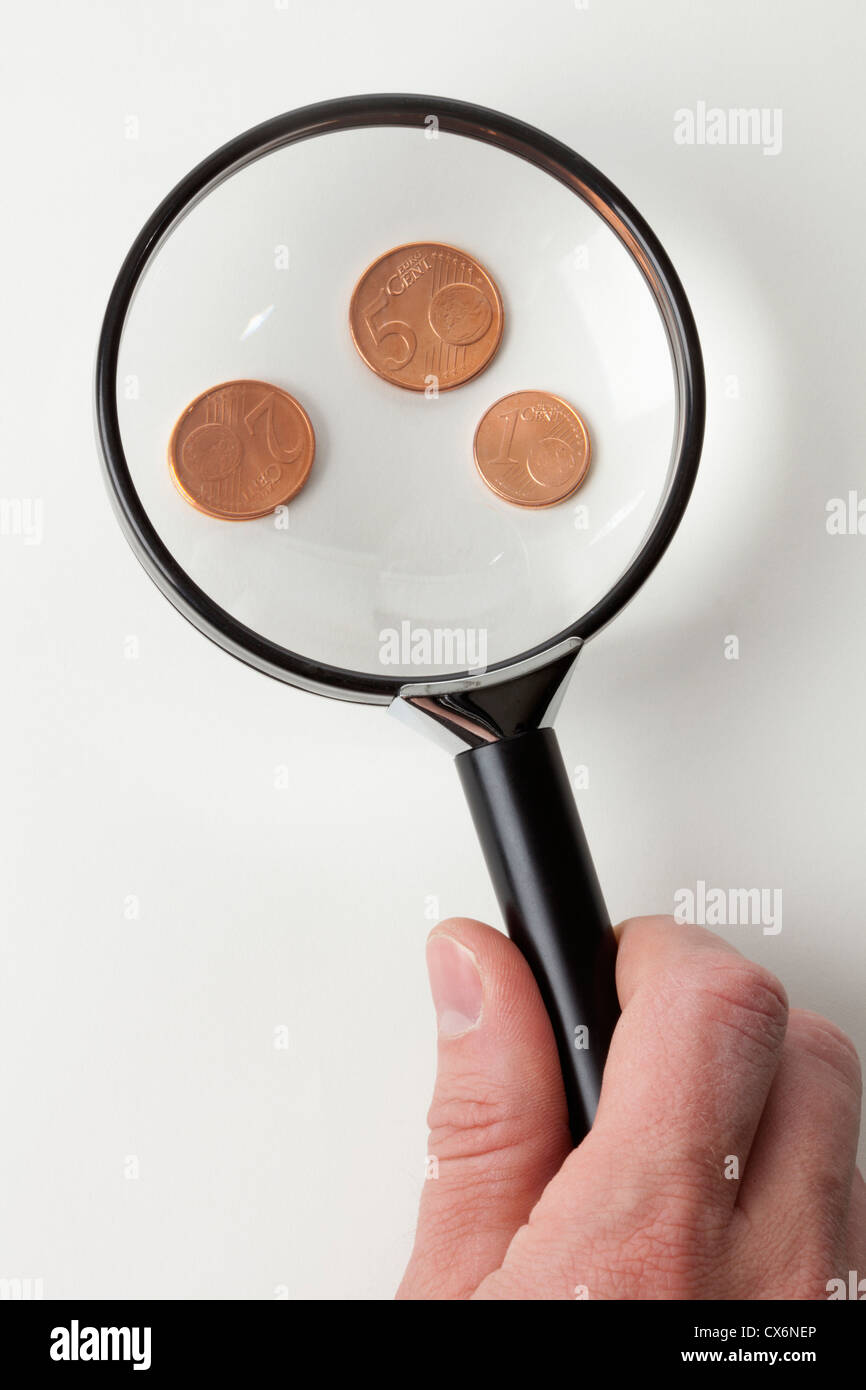 Ein Mann Lupe drei Euro Kupfermünzen, close-up von hand Stockfoto